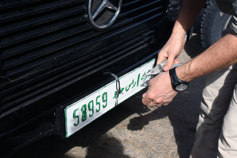 Pritrjevanje libijskih registrskih tablic. Vsak avto je dobil svoje. Dve. Brez heca. Foto Drago